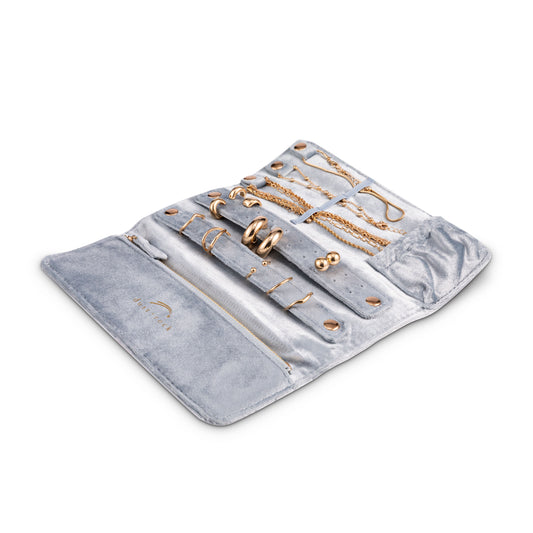 Dust and Rock Jewellery Wrap – light blue suede-style foldable organiser displayed open with storage for rings, necklaces, earrings, and bracelets; includes zip pocket, snap-secure holders, and soft protective lining. Compact travel jewellery case for women.
