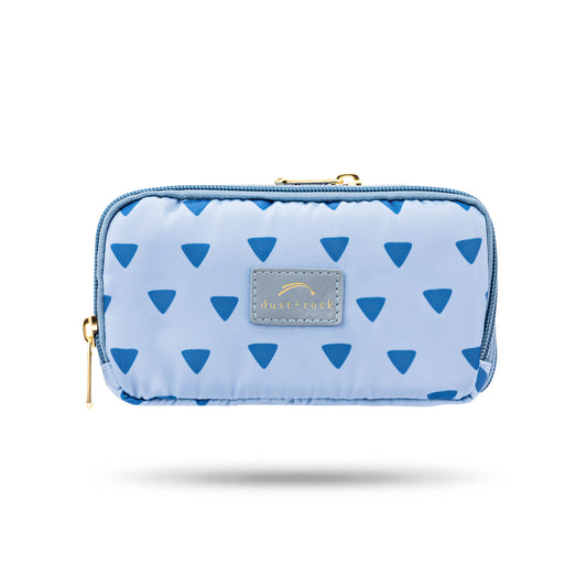 Dust and Rock Original Wrist Pocket – 'Silence' edition in soft blue with navy triangle print and gold zip; a stylish hands-free wrist wallet that fits a passport, perfect for travel, work, and daily errands with a calming aesthetic.