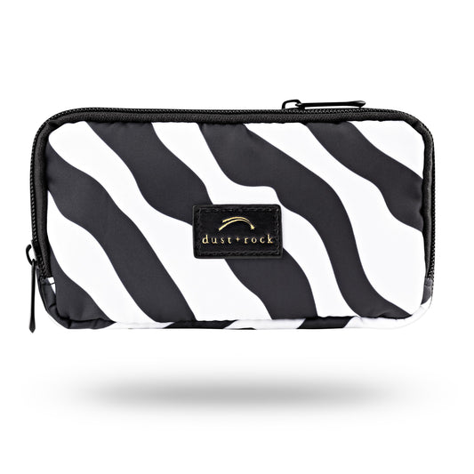 Dust and Rock Original Wrist Pocket – 'Sirius' edition with bold black and white zebra print; a passport-sized, hands-free wrist wallet perfect for travel, nights out, festivals, and everyday style.