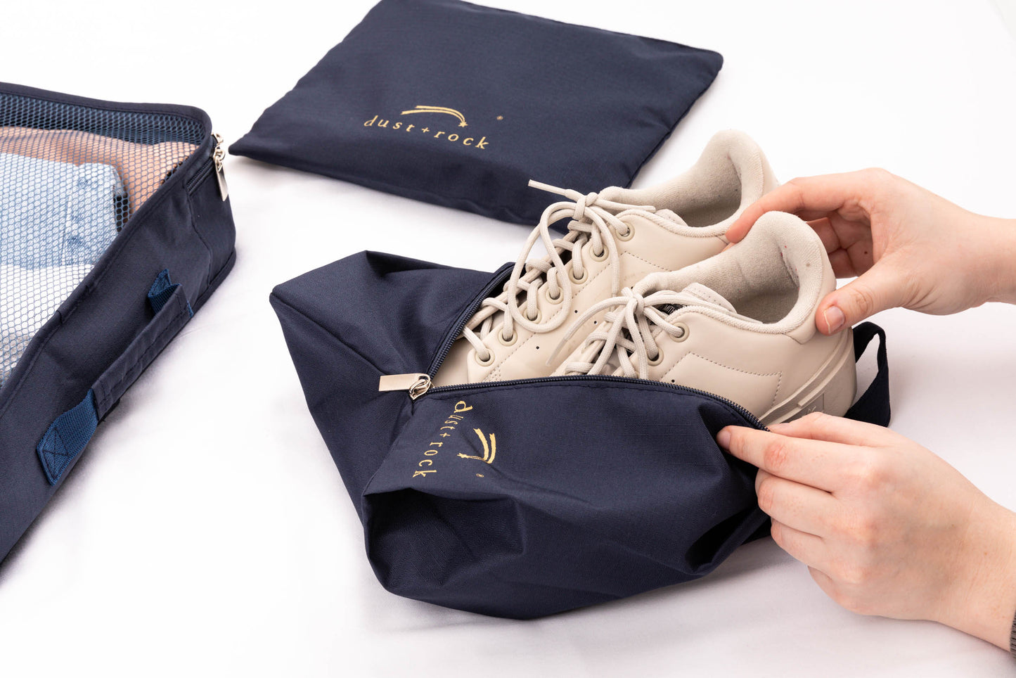 Person placing shoes into Dust and Rock Shoe Bag, designed to keep footwear separate and protect clothes from dirt during travel